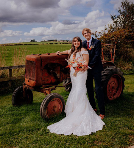 Couple standing in front of an old tractor